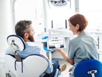 A rear view of man and dentist in dental surgery, annual check-up.