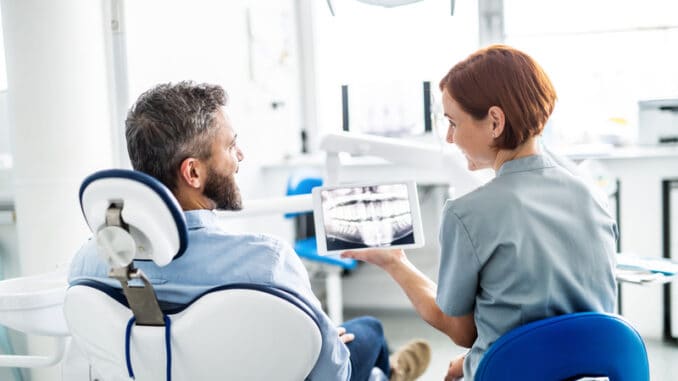 A rear view of man and dentist in dental surgery, annual check-up.