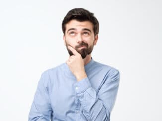 Thinking hispanic man looking up rubbing his chin isolated on white background.