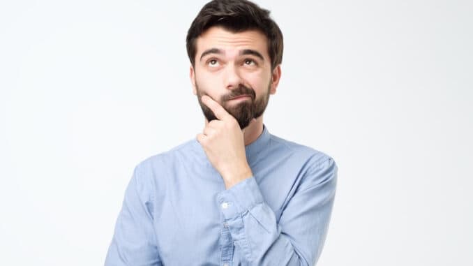 Thinking hispanic man looking up rubbing his chin isolated on white background.