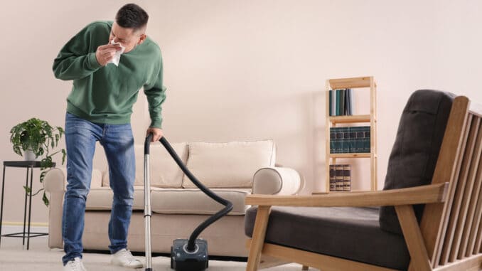 Man with dust allergy cleaning his home