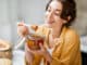 Portrait of a young and cheerful woman with a jar full of sweet honey on the kitchen at home