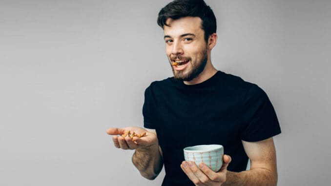 Casual looking guy hold bowl and some walnuts in hand