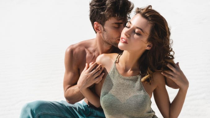 Passionate young couple kissing on beach with closed eyes