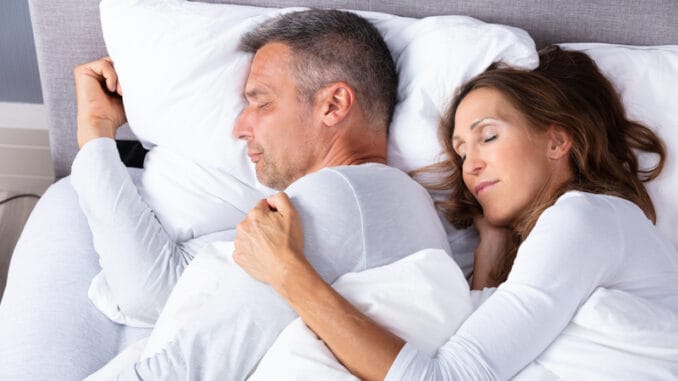 Mature Loving Couple Sleeping On Bed With White Blanket