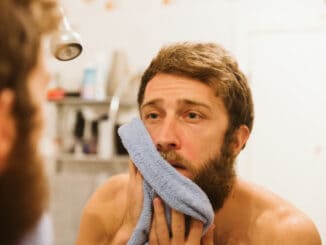 Young attractive man looking in mirror in morning