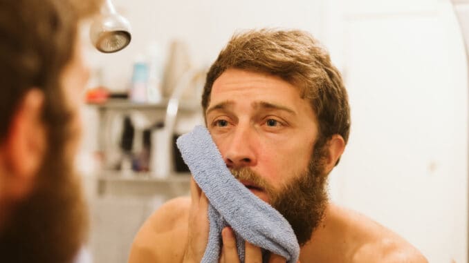 Young attractive man looking in mirror in morning