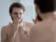 Young caucasian man wash brush teeth in bathroom have painful feeling suffer from gingivitis or periodontitis, millennial male struggle with oral dental problems, gums bleeding or inflammation