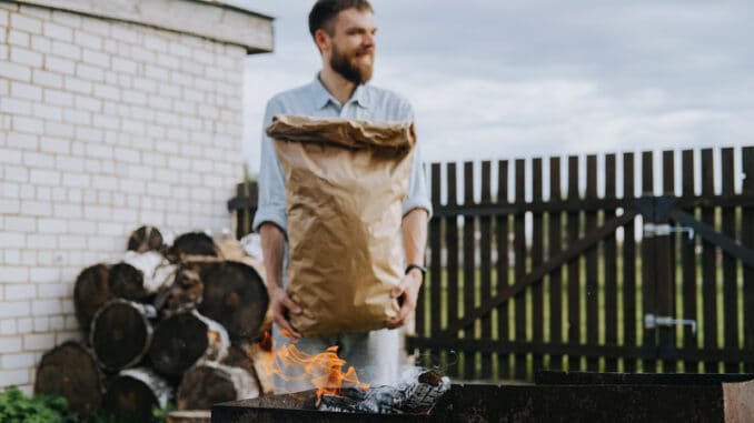dreamstime_s_186399157 A man with a craft bag of charcoal in his hands.