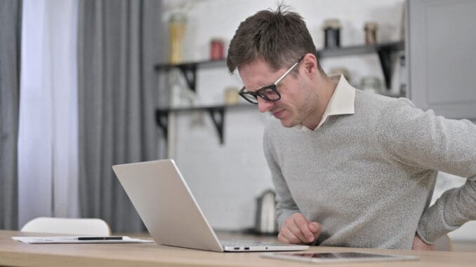 The Young Man with Spinal Back Pain Working on Laptop