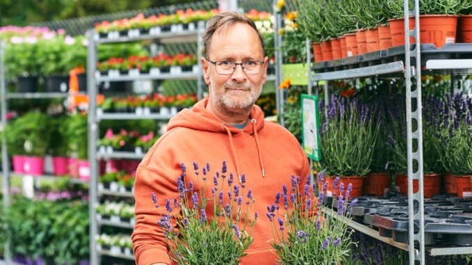 Middle age man gardener buying plants in garden center