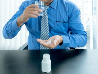 Young Asia businessman taking and eating medicines pill