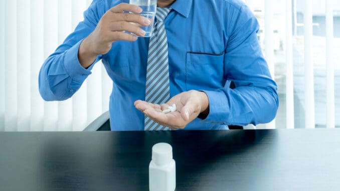 Young Asia businessman taking and eating medicines pill