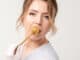 Portrait of beautiful young caucasian woman eating honey with wooden spoon on white background