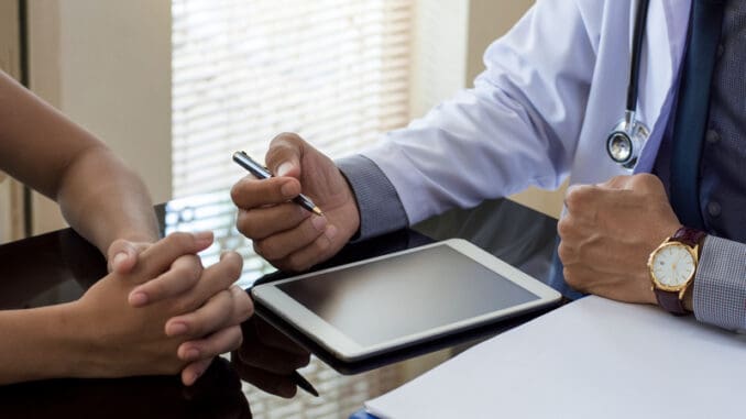 physician talking to patient with digital tablet