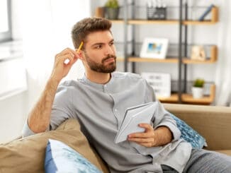 man writing to notebook and thinking at home