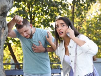 Woman calling ambulance to help man with heart attack