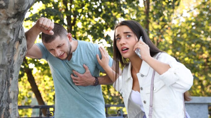 Woman calling ambulance to help man with heart attack