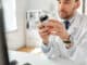 Healthcare, medicine and people concept - smiling male doctor with drug in jar at hospital