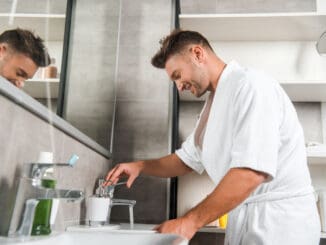 Side view of happy man in bathtub standing in bathroom