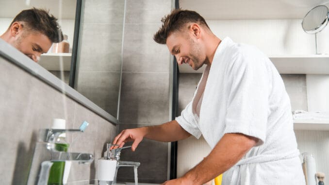 Side view of happy man in bathtub standing in bathroom