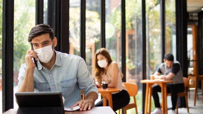 People wearing surgical masks are sitting in restaurants