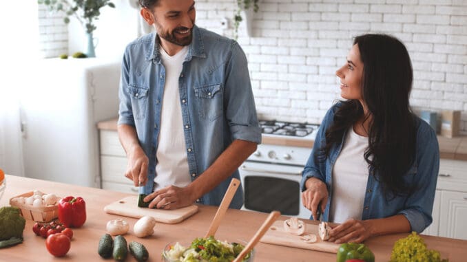 dreamstime_s_212036633 Smiling women and men cooking salad in the kitchen together.