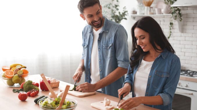 Caucasian couple preparing salad in the kitchen.