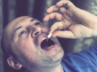 Extreme closeup man face taking white pill