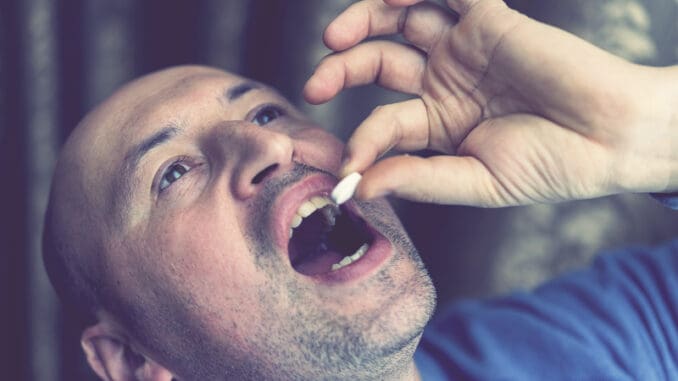 Extreme closeup man face taking white pill