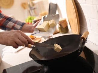 Man putting butter into frying pan
