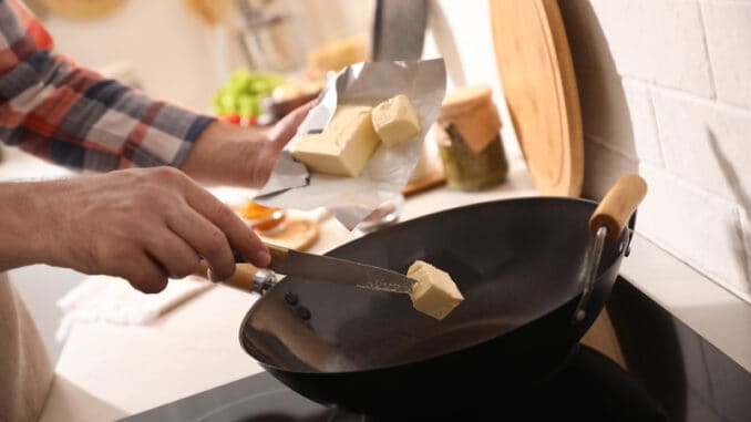 Man putting butter into frying pan