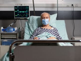Portrait of sick senior man patient with chirurgical mask resting in hospital bed