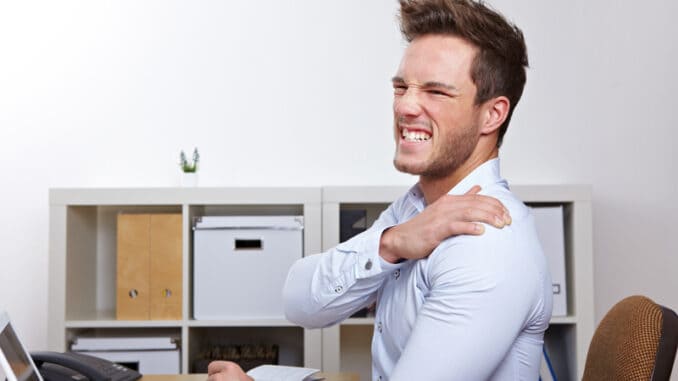 Business man with shoulder pain in office at desk