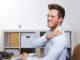 Business man with shoulder pain in office at desk
