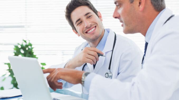 Doctors talking together about something on their laptop in medical office