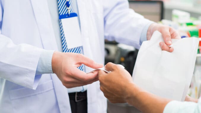 Cropped image of salesperson giving check and treatment in the drugstore on the foreground