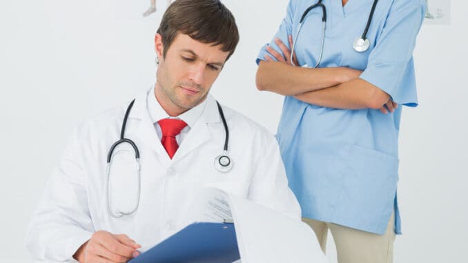dreamstime_s_37209443 Concentrated male doctor reading reports beside a nurse in the medical office