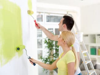 Affectionate couple painting together a room in their new house
