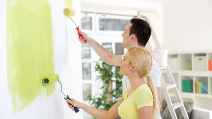 Affectionate couple painting together a room in their new house