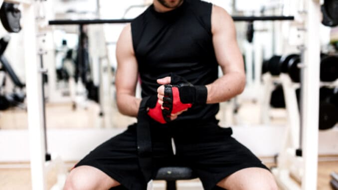 Man at gym preparing for workout, putting gloves on