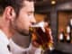 Side view of handsome young man drinking beer while sitting at the bar counter