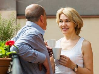 Happy mature couple drinking coffee and discussing at balcony