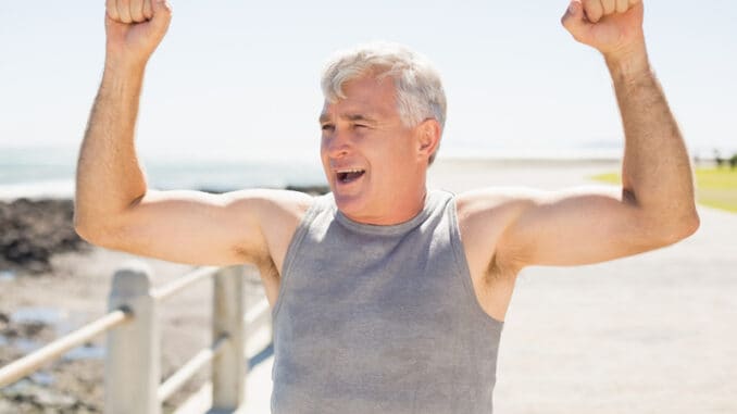 Fit mature man cheering on the pier on a sunny day