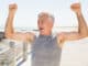 Fit mature man cheering on the pier on a sunny day