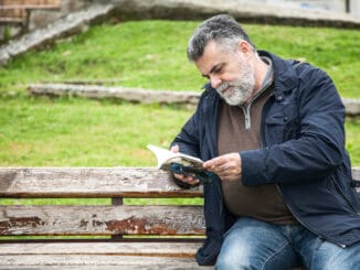 Attractive bearded man reading in a big park