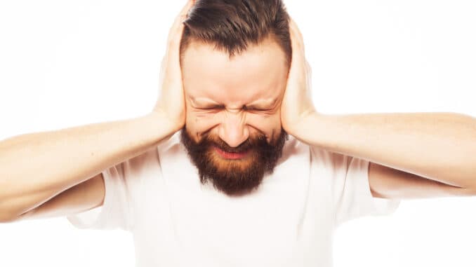 bearded man covering his ears by hands