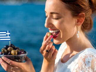 Smiling woman eating fresh green and black olives
