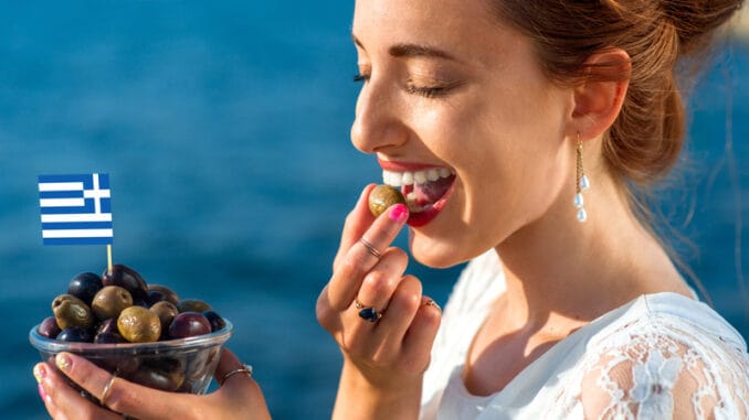 Smiling woman eating fresh green and black olives