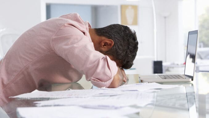 Stressed Man Working At Laptop In Home Office